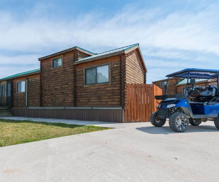 wood cabin exterior with grass and golf cart