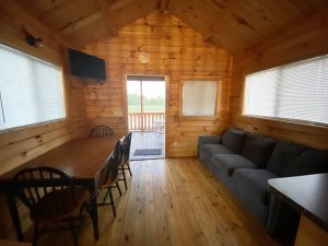 interior of wood cabin with large couch, dining area/table, and TV