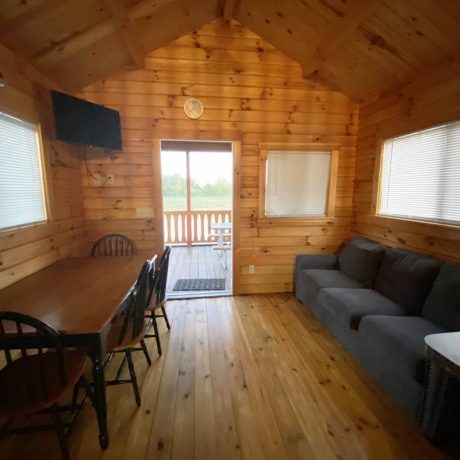 interior of wood cabin with large couch, dining area/table, and TV